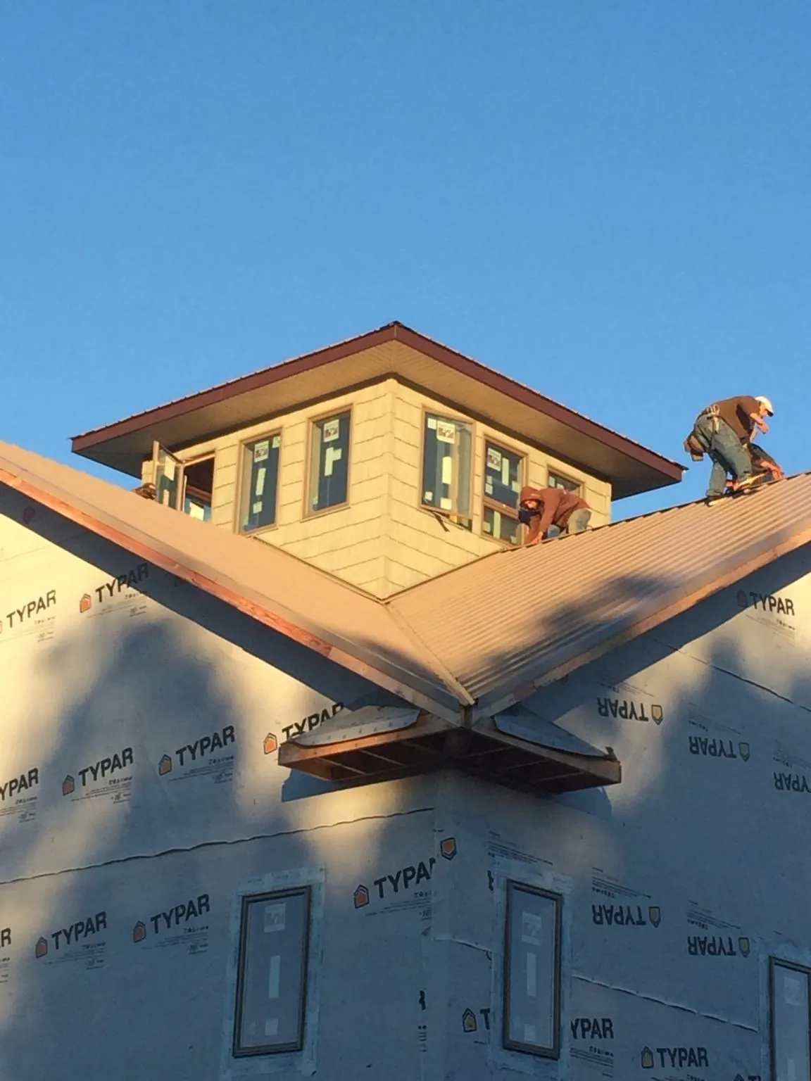 Roofers working around a rooftop cupola on a new metal roof at sunset — Roof Waterproofing in Pinson by Roofing Brothers